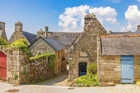 Alley in an old idyllic french villages with picturesque stone houses with lush green garden