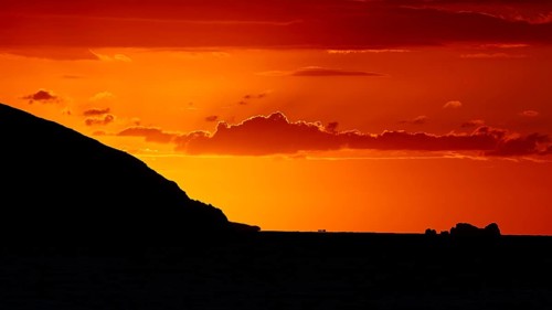 Dramatic sunset over the sea with a silhouetted island and a bright orange sky, sunset, Kassos,