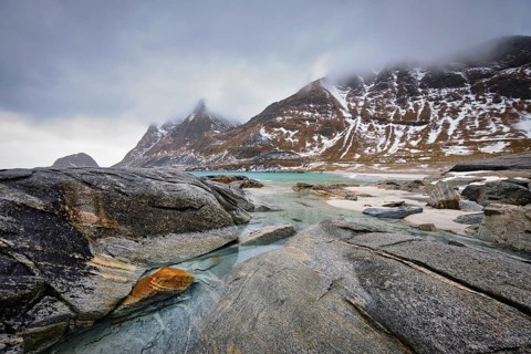 Rocky coast of fjord of Norwegian sea in winter with snow. Haukland beach, Lofoten islands, Norway,
