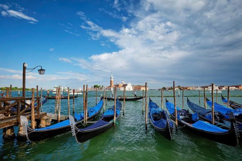 VENICE, ITALY, JUNE 27, 2018: Gondolas and gondolier in lagoon of Venice by Saint Mark (San Marco)