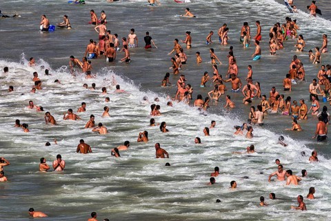 View from above on crowd in the surf, tourists swimming in the sea, enjoying cooling off, fun,