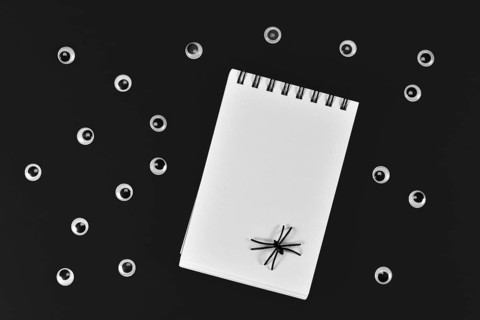 Halloween eyes, empty notebook and spiders on black backgroound