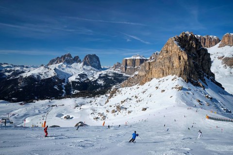 View of a ski resort piste with people skiing in Dolomites in Italy. Ski area Belvedere. Canazei,