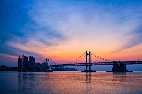 Gwangan Bridge on sunrise with skyscrapers and dramatic sky. Busan, South Korea, Asia