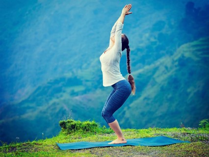 Young sporty fit woman doing yoga asana Utkatasana (chair pose) outdoors in mountains Himalayas in