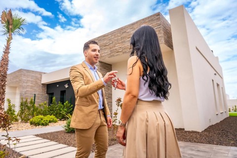 Woman receiving the keys of a new house outside the building