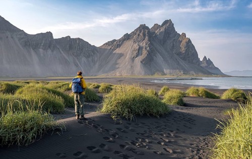 Tourist on a sand dune, Black beach with volcanic sand, Sand beach, Dunes with grass, Stokksnes