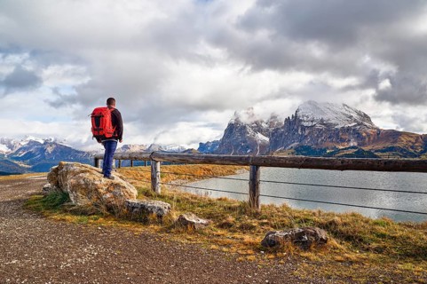 Hiker standing on stone, Sassopiatto, Sassolungo, Dolomites, Alpe di Siusi, lake, snow, clouds,