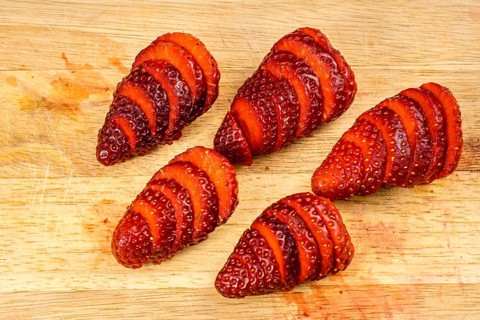 Natural strawberries cut slices on a wood