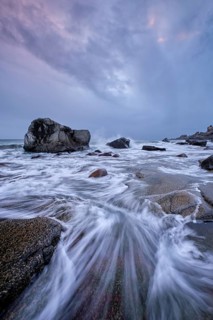 Rocks on beach of fjord of Norwegian sea in winteron sunset. Utakliev beach, Lofoten islands,