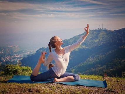 Yoga outdoors, young sporty fit woman doing stretching yoga asana Eka pada rajakapotasana,