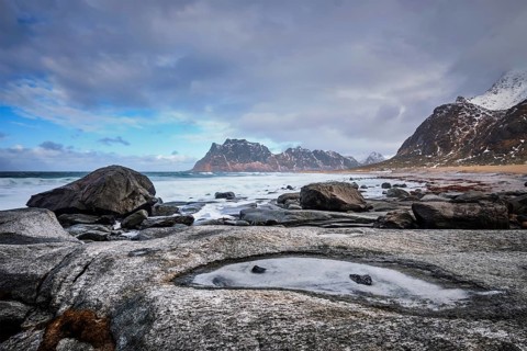 Rocks on beach of fjord of Norwegian sea in winter with snow. Utakliev beach, Lofoten islands,