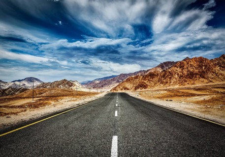 Travel forward concept background, road in Himalayas mountains and dramatic clouds. Ladakh, Jammu