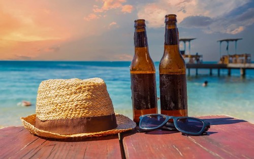 Two beers, sunglasses and a hat on West End beach on Roatan Island. Honduras