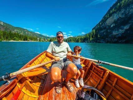 Tourists rowing a wooden boat on lake braies, surrounded by stunning mountain scenery in the