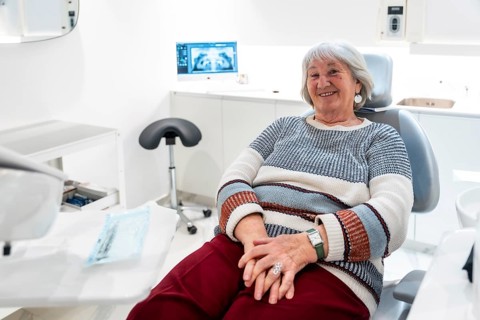 Elderly patient smiling and feeling comfortable during a dental checkup in a bright, modern clinic,