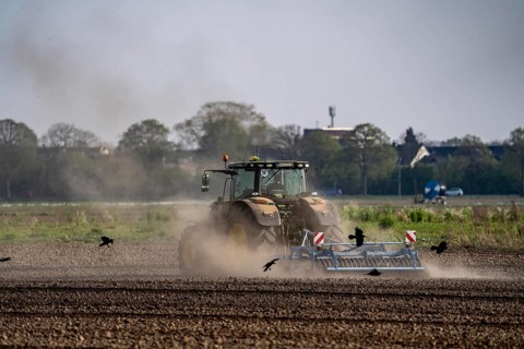 A tractor works a field, due to long dryness in spring, no rain for more than 4 weeks, the fields