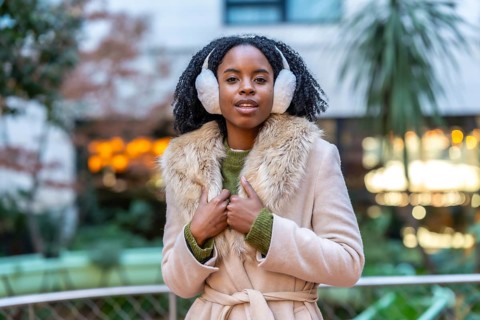 Fashionable young woman enjoys winter day in the city, wearing stylish earmuffs and a warm coat