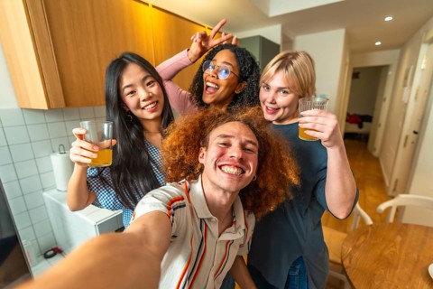 Group of cheerful multi ethnic friends taking a selfie while enjoying glasses of juice together in