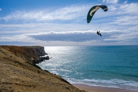 Sagres, Algarve, Portugal - Paraglider flying on the town beach Praia da Mareta, at the back left