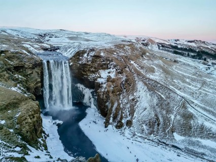 Drone aerial view of frozen Skogafoss waterfall filled with snow in winter in Iceland