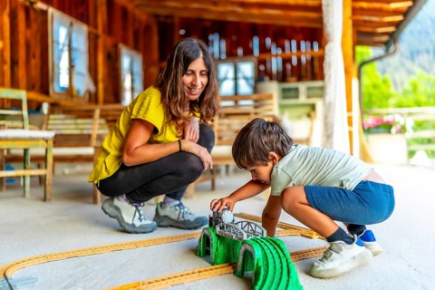 Mother and son enjoying quality time, playing with a toy train set on a rustic porch