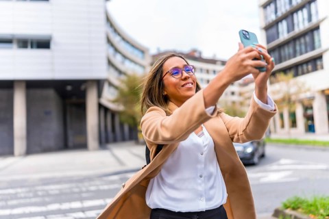 Latin woman visiting a city and taking photos with mobile phone enjoying the day in the city