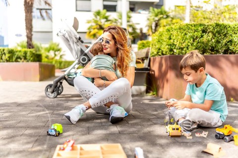Mother embracing a baby while playing with his son in a park