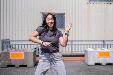 Urban female asian young dancer dancing k-pop in the city in an urban industrial space