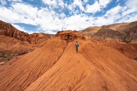 Mountaineer on a mountain ridge, eroded mountain landscape with sandstone rocks, canyon with red