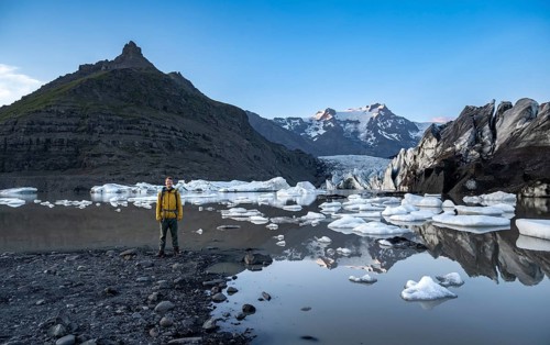 Hikers at a lake, reflection in the Svínafellslon glacier lagoon with ice floes, Svínasfellsjökull