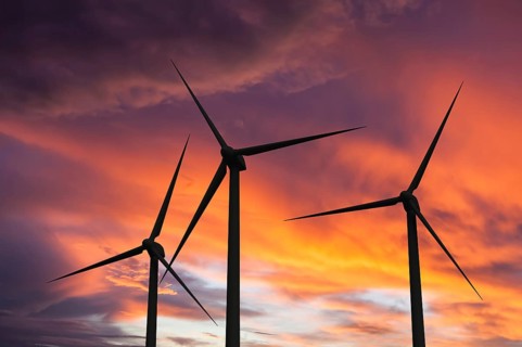 Green renewable energy concept, wind generator turbines in sky on sunset