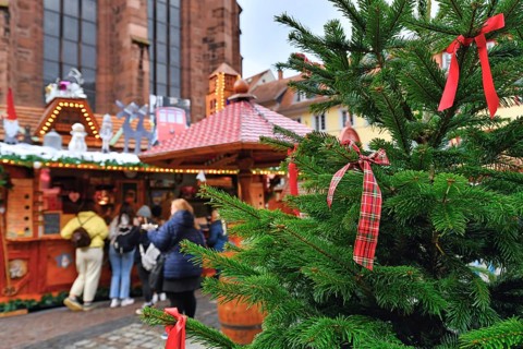 Heidelberg, Germany, December 2019: Close up of red ribbon tied to Christmas tree with sales booth