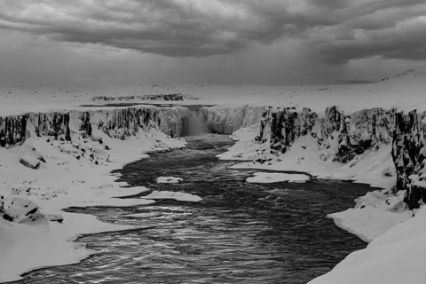 Selfoss waterfall with the river Jökullsa a Fjöllum, icy and snow-covered rock faces and shoreline,