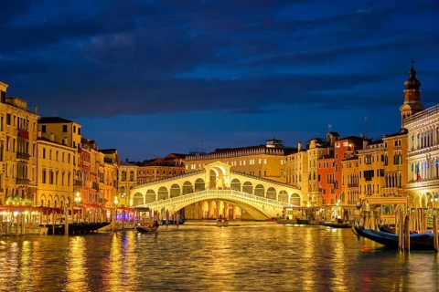 Famous Venetian tourist landmark Rialto bridge (Ponte di Rialto) over Grand Canal illuminated at