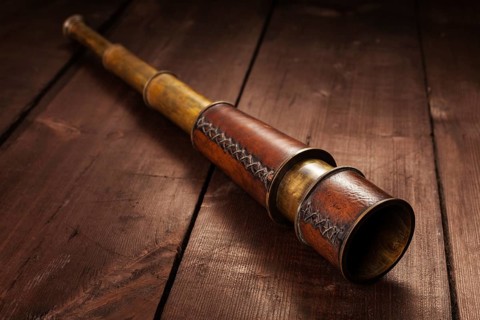 Vintage retro spyglass on wooden background