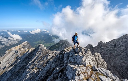 Mountaineer on a rocky narrow mountain path with mountain panorama, mountain tour to the summit of