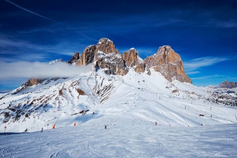 View of a ski resort piste with people skiing in Dolomites in Italy