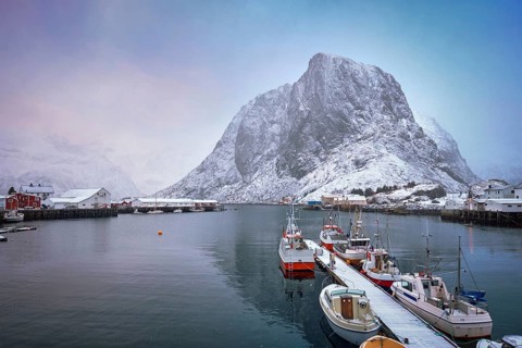 Pier with ships in Hamnoy fishing village on Lofoten Islands, Norway with red rorbu houses. With