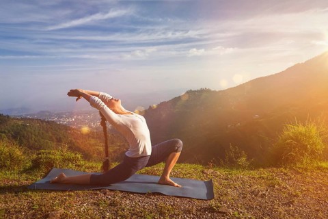 Yoga outdoors, sporty fit woman practices yoga Anjaneyasana, low crescent lunge pose outdoors in