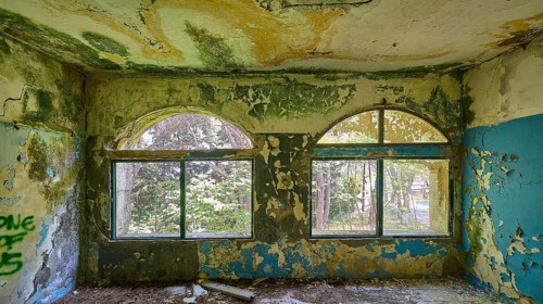 Dilapidated arched windows in an abandoned building with traces of decay and blue walls, Lost