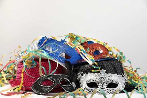 Various carnival masks and hats, surrounded by colourful streamers, carnival