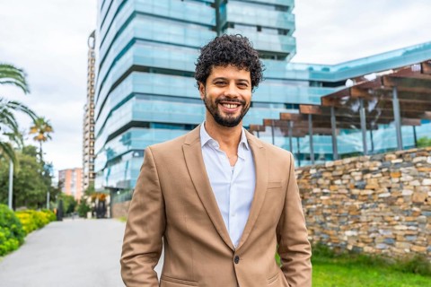 Frontal portrait of a Latin smiling businessman with hands on pockets standing proud outdoors in