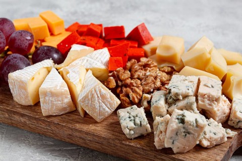Assorted cheese on a wooden board, with grapes and walnuts, appetizer, no people