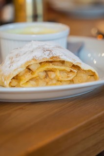 Close-up of an apple strudel with icing sugar and visible apple pieces on a plate, autumn creations