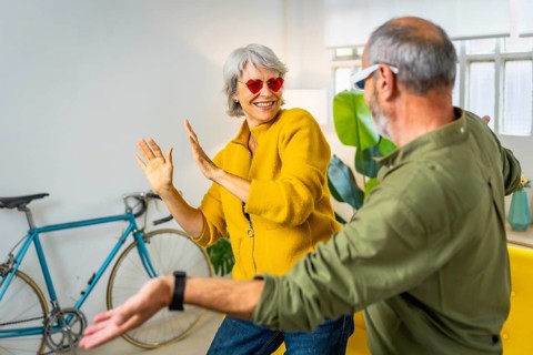 Modern senior couple with stylish sunglasses having fun together at home laughing and dancing