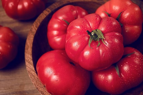 Pink tomatoes, in a rustic wooden bowl, close-up, no people