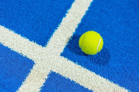 Paddle tennis yellow ball in a blue court with white lines