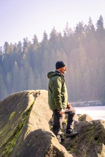 Man with outdoor clothes standing on a rock, surrounded by forest and sunlight, Glaswaldsee, Bad