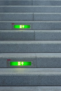 Public staircase with green illuminated emergency exit signs, Germany, Europe